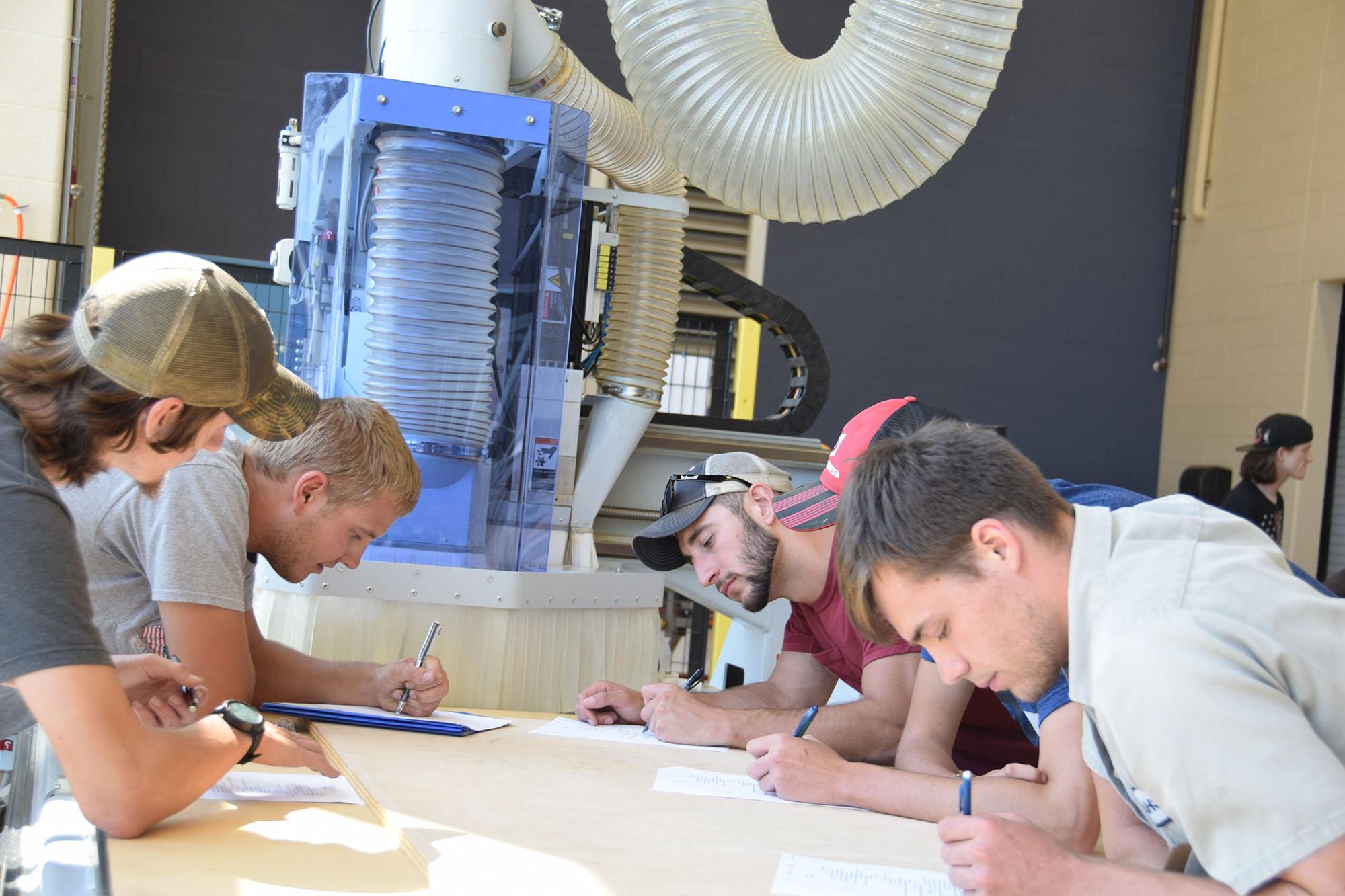 A group of students completing an assignment in front of a machine