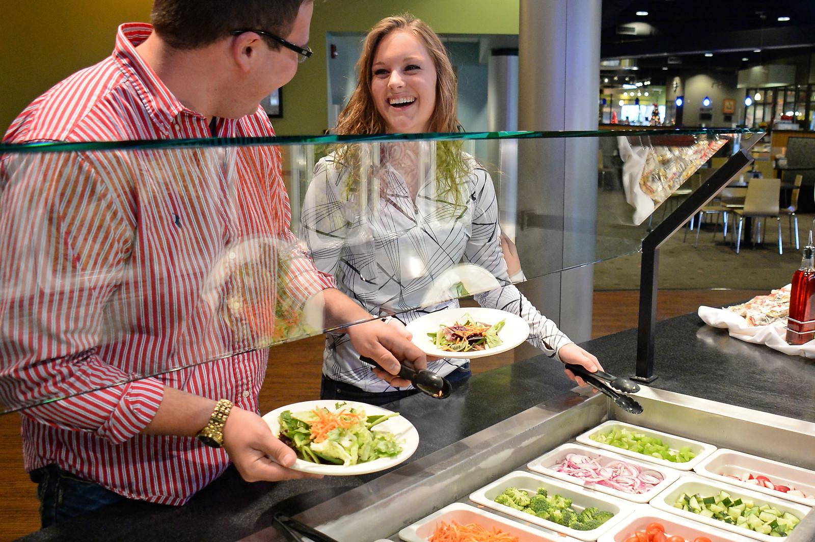 Two students getting salads from the salad bar