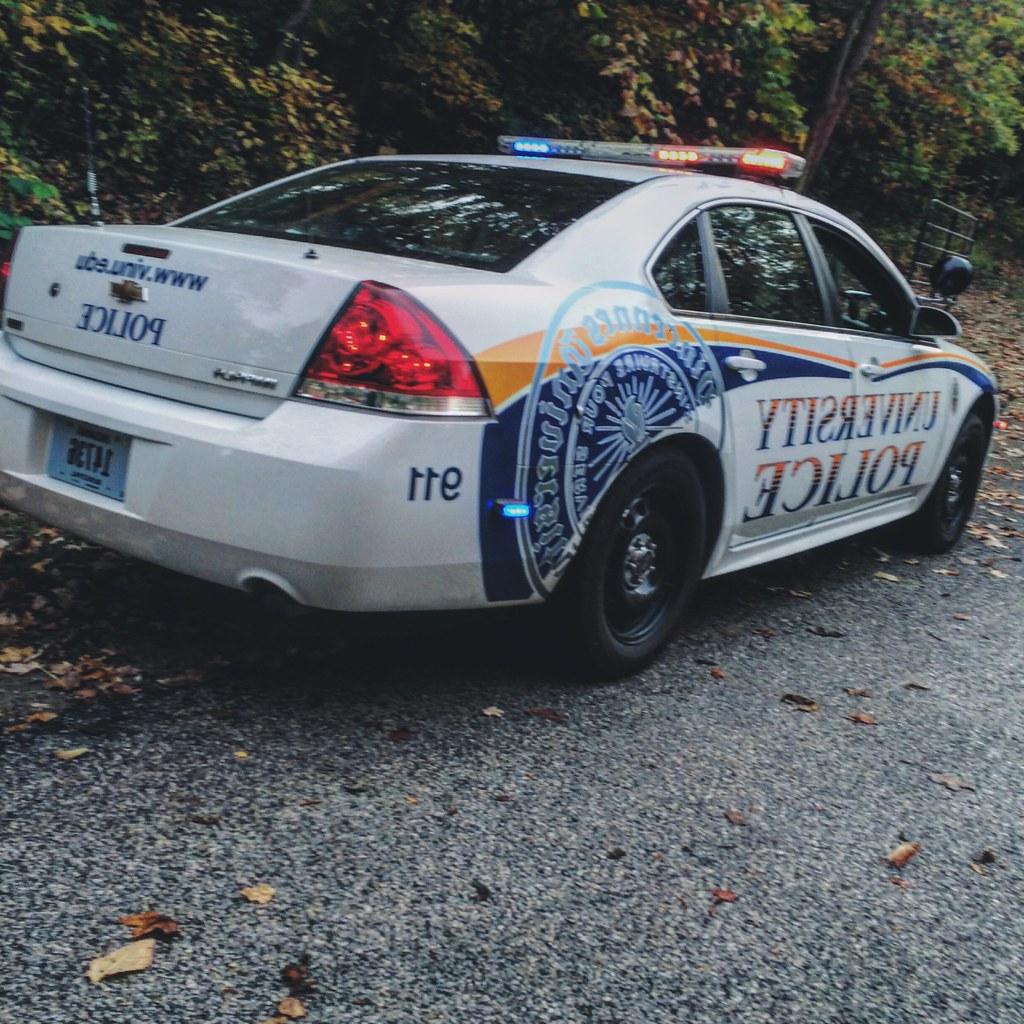 University  police car parked near the woods
