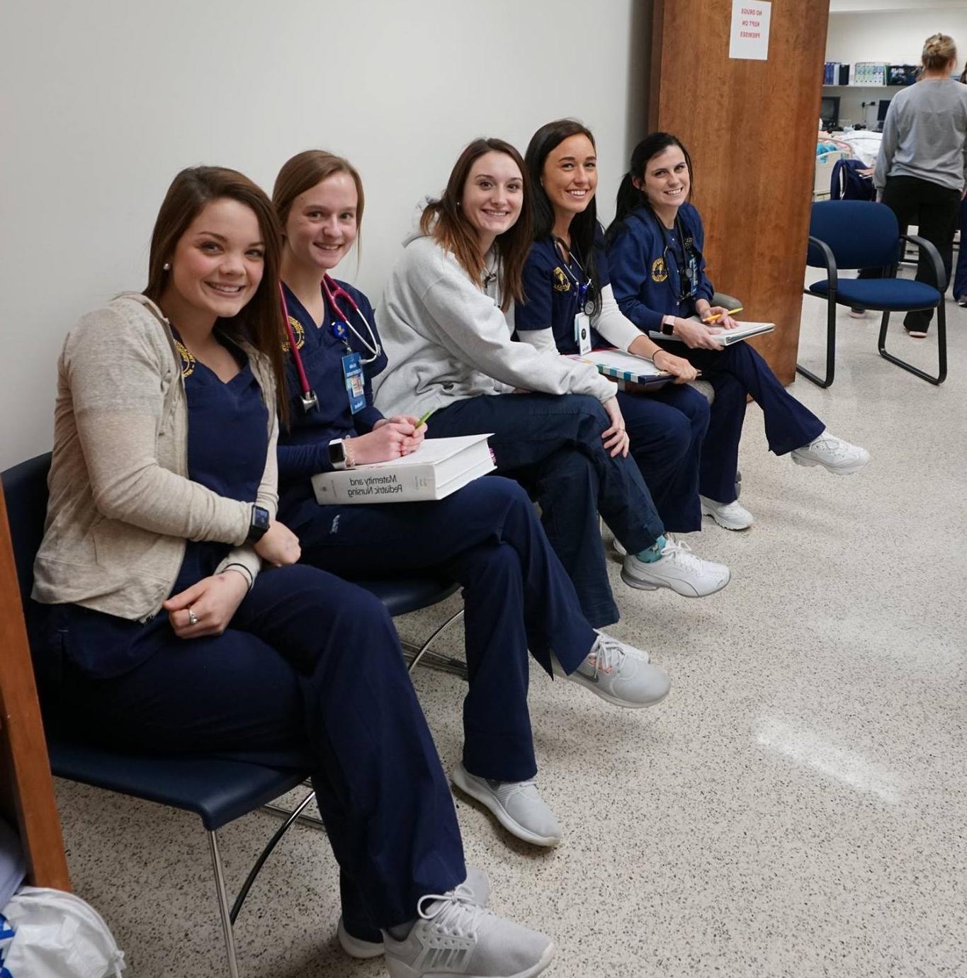 Nursing students sitting in desks while smiling for a photo