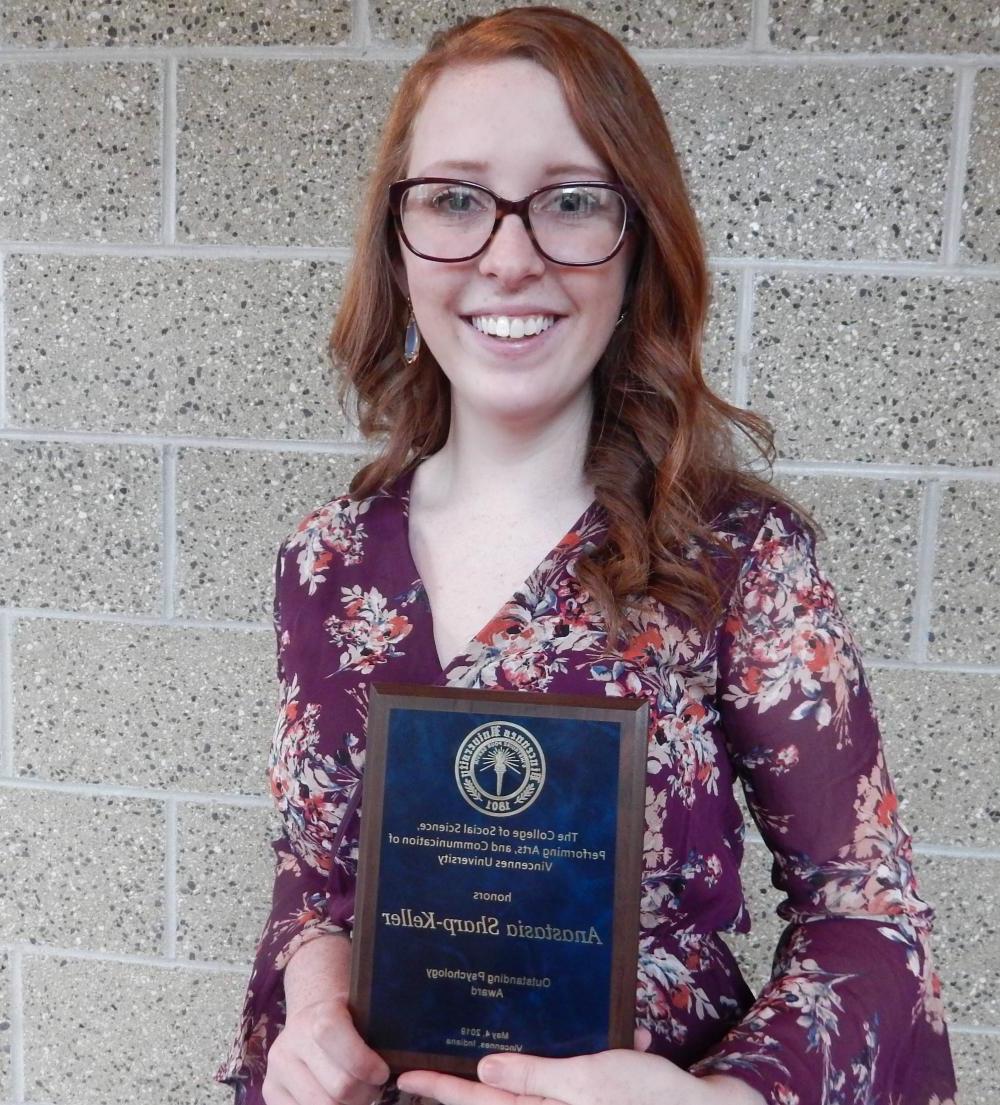 A female student holding an award for outstanding psychology